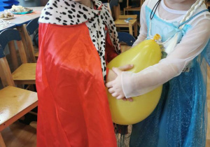 Dzieci tańcząc w parach trzymają brzuszkami balon